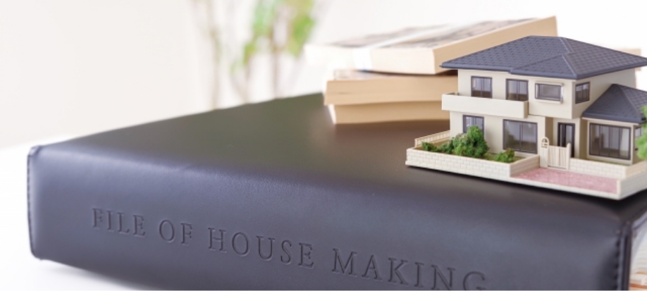 本の上にミニチュアの家の模型が置かれている画像